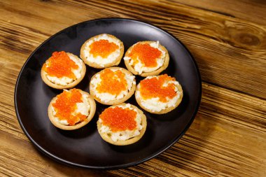 Kırmızı havyarlı turta ve ahşap bir masada yumuşak peynir.