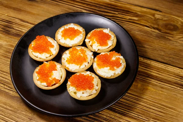 Kırmızı havyarlı turta ve ahşap bir masada yumuşak peynir.