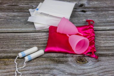 Tahta arka planda hijyenik ped, tampon ve regl kupası. Kritik günler, regl dönemi, kadın hijyeni
