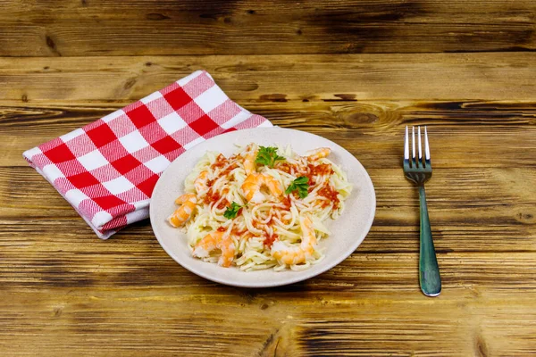 Karidesli makarna, domates sosu ve ahşap masada maydanoz.