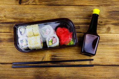 Uramaki suşisi, tahta masadaki plastik kutuda surimi ile yuvarlanır. Üst Manzara. Plastik kabın içinde suşi götürmek ya da teslim etmek için suşi