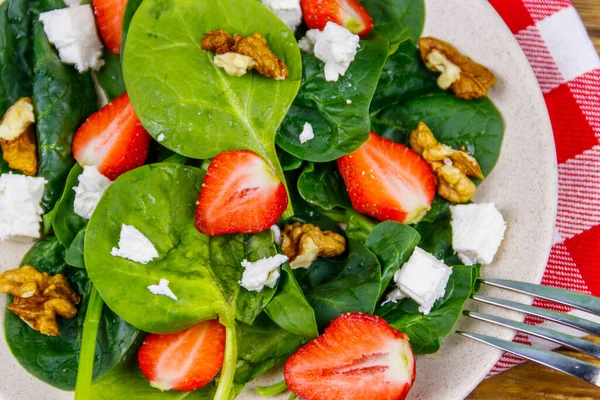 Tahta masada çilekli, ıspanaklı, cevizli ve peynirli taze sağlıklı salata.