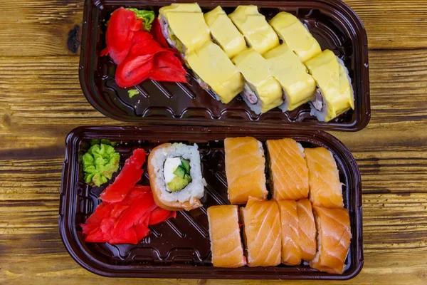 一套寿司卷在木制桌子上的塑料盒里 顶部视图 寿司用塑料容器盛放寿司的寿司 — 图库照片