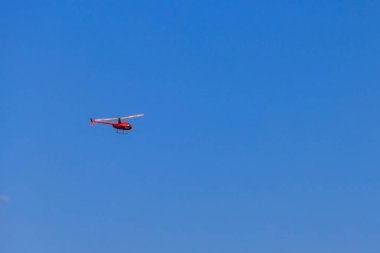 Mavi gökyüzünde uçan turuncu helikopter