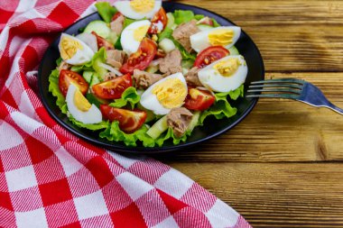 Yumurtalı lezzetli ton balığı salatası, marul ve ahşap masada taze sebze.