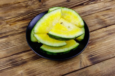 Tahta bir masada, taze, olgun, sarı bir karpuz.