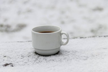 Kışın karlı bir masada bir fincan kahve.