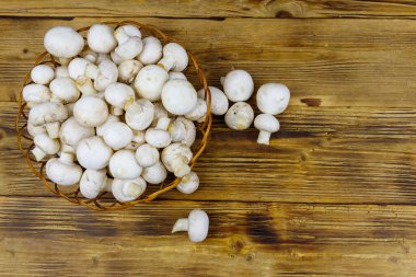 Tahta masada hasır sepetin içinde taze şampiyon mantarları. Üst görünüm