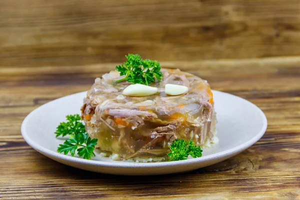 Meat aspic in a plate on a wooden table. Traditional russian dish