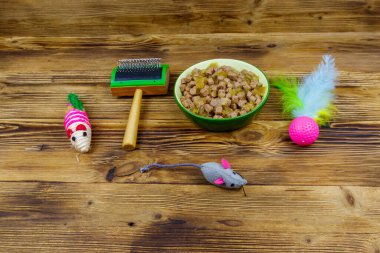 Kasede konserve kedi maması, kedi oyuncakları ve ahşap arka planda evcil hayvan fırçası. Hayvan bakımı konsepti