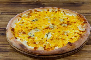 Tahta arka planda dört peynirli pizza.