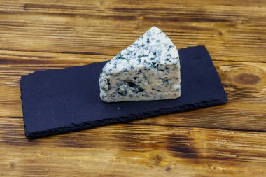 Ahşap masada siyah tahta servis edilen küflü mavi peynir.