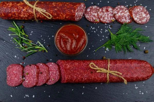 Salamlı sosis, ketçap ve siyah tahtada baharatlar. Üst görünüm