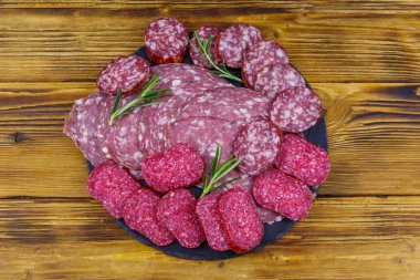 Ahşap masadaki siyah tahtada farklı bir dilimlenmiş salam sosisi. Üst görünüm