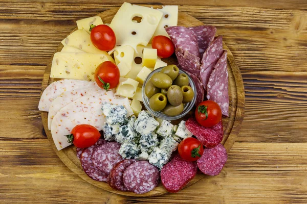 Antipasti platter with olives, cherry tomatoes, assortment of italian salami and cheese on a wooden table. Top view