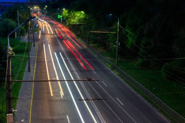 Gece şehir caddesinde araba ışığı izleri var.