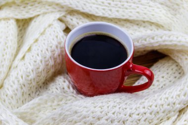Etrafında beyaz örülü eşarp olan bir fincan kahve. Kış konsepti