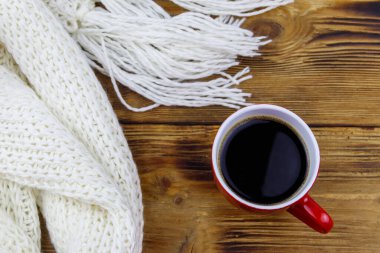 Ahşap masada örülmüş beyaz eşarp ve bir fincan kahve. Üst Manzara. Kış konsepti