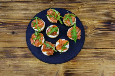 Somonlu tart, krem peynir ve ahşap masada roka. Üst görünüm