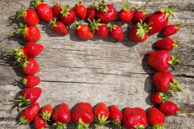 Taze kırmızı çilek çerçevesi ahşap masa üstünde fotokopi alanı manzaralı.