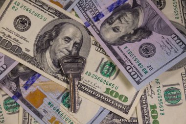 Yüz dolarlık banknotların arka planında anahtar var. Ev alma veya kiralama kavramı
