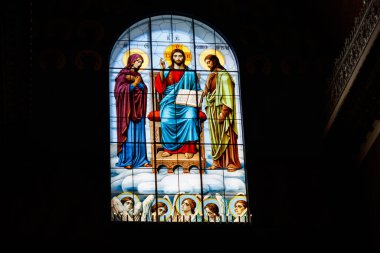 İsa 'yı, Bakire Meryem' i ve Vaftizci Yahya 'yı tasvir eden lekeli cam pencere.