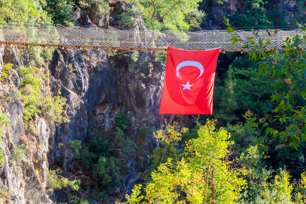 Турецкий флаг, висящий на подвесном деревянном мосту в каньоне Гейнук в провинции Анталья, Турция