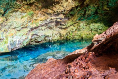 Kayalık bir mağarada dikitler ve dikitlerle oluşmuş güzel bir kristal berrak su havuzu manzarası. Tanzanya, Zanzibar 'daki Kuza mağarası