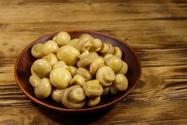 Seramik tabak turşusu petrol ile. Ahşap masa üzerinde Marine mantar