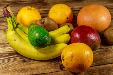 Ahşap masa üzerinde tropikal meyve çeşitleri. Muz, mango, portakal, avokado, greyfurt ve kivi ile natürmort