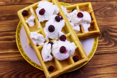 Dondurmalı Belçika waffle 'ı ve ahşap masada böğürtlen.
