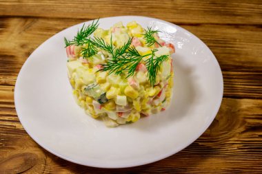 Yengeç çubuklu salata, tatlı mısır, salatalık, yumurta ve mayonez ahşap masada.