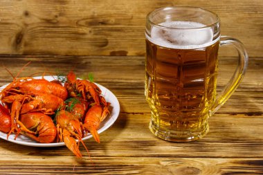 Haşlanmış kerevit ve bir kupa bira ahşap masada.