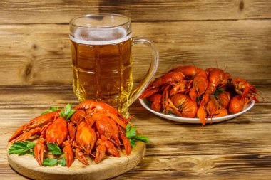 Haşlanmış kerevit ve bir kupa bira ahşap masada.
