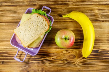 Sandviç, muz ve elmayla dolu bir beslenme çantası. Üst görünüm