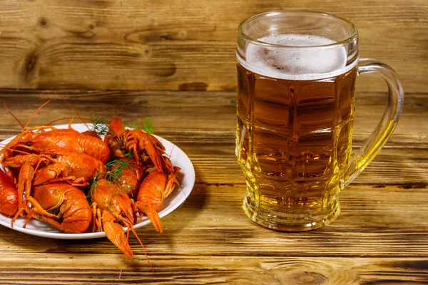 Haşlanmış kerevit ve bir kupa bira ahşap masada.