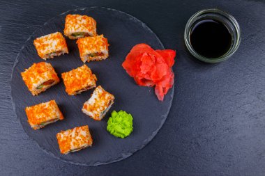 Suşi Philadelphia 'yı siyah bir levhada yuvarlıyor. Üst görünüm