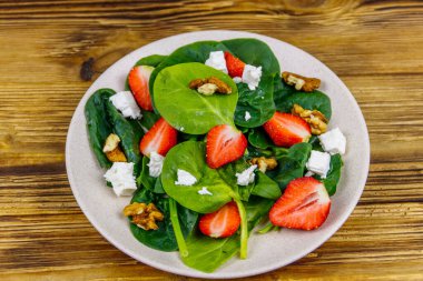 Tahta masada çilekli, ıspanaklı, cevizli ve peynirli taze sağlıklı salata.