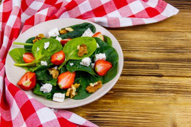 Tahta masada çilekli, ıspanaklı, cevizli ve peynirli taze sağlıklı salata.