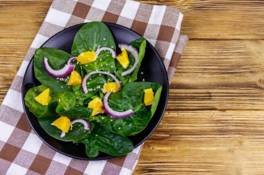 Tahta masada ıspanaklı, portakallı, kırmızı soğanlı ve susamlı lezzetli salata. Üst Manzara. Sağlıklı gıda veya vejetaryen konsepti