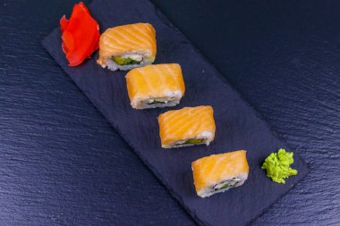 Suşi Philadelphia 'yı siyah bir levhada yuvarlıyor. Üst görünüm