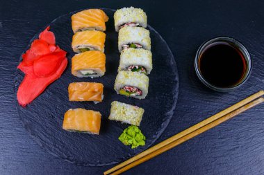 Suşi seti siyah bir taş tahtada yuvarlanıyor. Üst görünüm