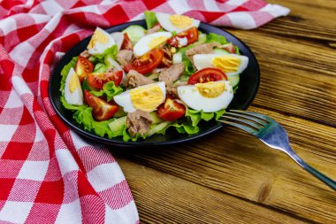 Yumurtalı lezzetli ton balığı salatası, marul ve ahşap masada taze sebze.