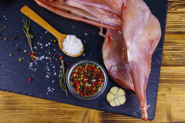 Ahşap masanın üzerinde siyah bir tahta üzerinde baharatlı çiğ tavşan eti. Üst görünüm