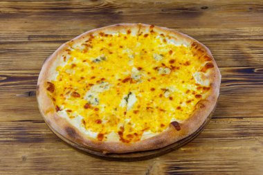 Tahta arka planda dört peynirli pizza.