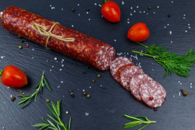 Siyah tahta üzerinde vişneli domates ve baharatlı salam sosisi. Üst görünüm