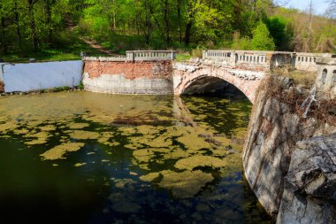 Ukrayna 'nın Kharkov bölgesindeki Sharovka Sarayı parkındaki bir gölette eski kemerli tuğla köprü.