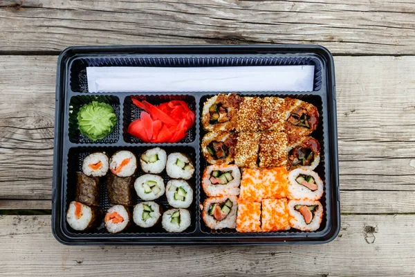 一套寿司卷在木制桌子上的塑料盒中 寿司用塑料容器运送或带走寿司 顶部视图 — 图库照片