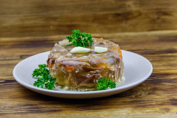 Meat aspic in a plate on a wooden table. Traditional russian dish