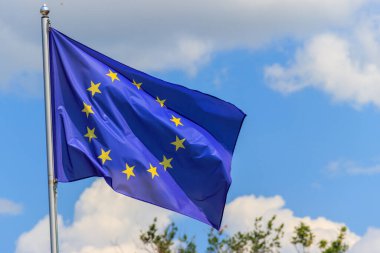 Mavi gökyüzüne karşı Avrupa Birliği bayrağı sallıyor